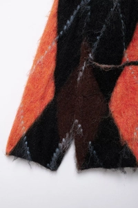 Detail shot of soft argyle knit fabric in orange and black with split hem design