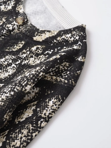 Vista macro di un cardigan in maglia animalier con bottone in ambra e scollatura a coste