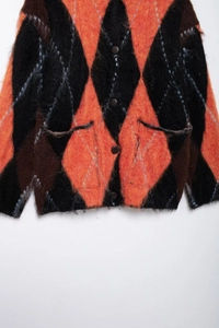 Detail view of the soft mohair texture and classic argyle pattern on a knit cardigan