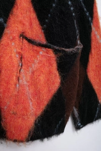 Detailed close-up of textured argyle knit fabric with soft mohair feel and side pocket