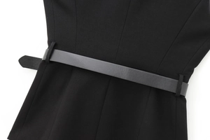 Détail de la taille d'une robe noire cintrée avec ceinture en similicuir et plis délicats