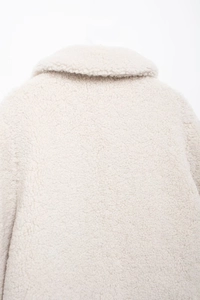Detailed close-up of cream white fleece texture on the collar of a stylish winter jacket