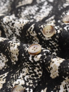 Dettaglio macro di bottoni in tartaruga e stampa animalier sul cardigan in maglia