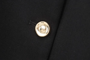 Gros plan d'un bouton métallique doré poli sur le tissu d'un gilet sans manches noir