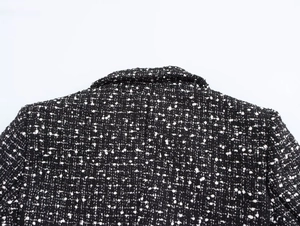 Close-up of the black and white textured tweed fabric on the collar and shoulder area