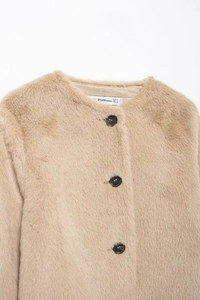 Gros plan sur une veste en fausse fourrure marron clair avec grands boutons en écaille et col rond