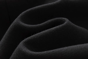 Gros plan macro d'un tissu en maille noire montrant une texture douce et un tissage fin