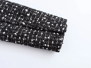Detailed macro view of black and white tweed fabric texture on a double-breasted blazer