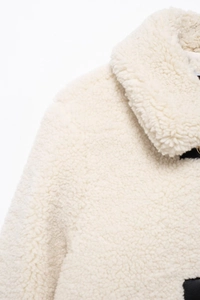 Detailaufnahme der weichen cremefarbenen Webpelzjacke mit modischem Kragen und Revers