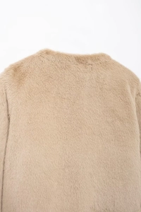 Gros plan de la texture en fausse fourrure beige sur le col et l'épaule du blouson