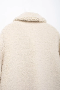 Detaillierte Nahaufnahme der flauschigen Textur und des Kragens dieser beigen Jacke