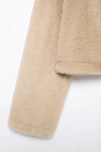 Détail de la texture en fausse fourrure sur les poignets et l'ourlet de la veste courte beige