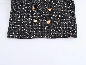 Macro shot of black and white tweed fabric texture with decorative gold metal buttons