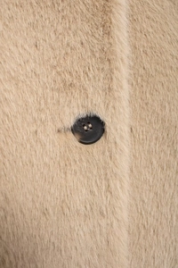 Gros plan sur la texture de fausse fourrure beige avec un gros bouton rond marron foncé