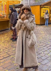 Detail of a beige teddy faux fur long coat with matching bucket hat and gold chain bag