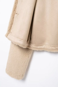 Détail de la texture en fausse fourrure beige et des coutures en daim sur une veste