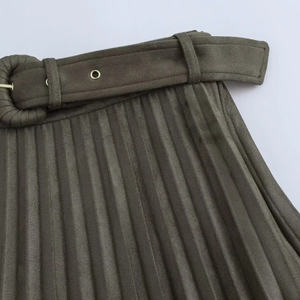 Détail d'une jupe plissée en daim vert olive avec ceinture assortie et œillets