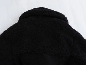 Detail view of high-quality black fleece texture and round neckline of a warm long coat