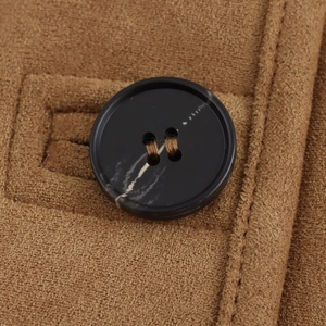 Macro shot of brown faux suede fabric with decorative marble-patterned black button and stitching