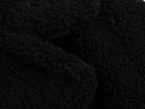Macro view of black sherpa fleece fabric showing thick and soft granular texture