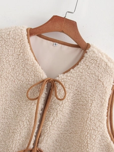 Detail of cream fleece vest featuring brown contrast piping and a lace-up neckline