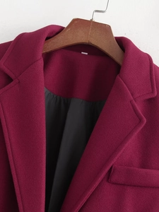 Macro shot of burgundy wool coat showing notched lapel, breast pocket and black lining