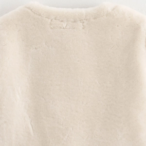 Gros plan sur le tissu pelucheux blanc crème et la couture du col d'une veste d'hiver