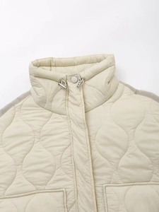 Détail d'une veste matelassée blanc cassé avec col montant et cordon de serrage en métal