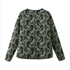 Close-up of olive green quilted jacket with black abstract prints and trimmed edges