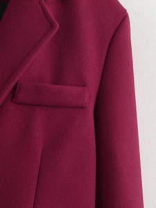 Detailed close-up of burgundy wool coat showing lapel, pocket, and textured fabric
