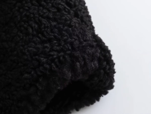 Close-up of premium black sherpa fleece fabric showing curly texture and soft material