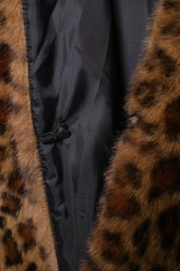 Dettaglio cappotto in pelliccia sintetica leopardata con fodera nera e chiusura elastica