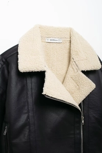 Détail de la veste de motard en similicuir noir avec col en peau de mouton beige et zips