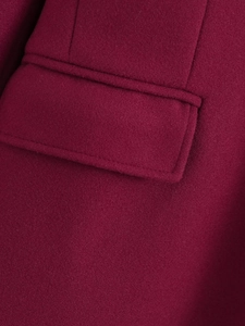 Detail of burgundy wool coat showing high-quality pocket flap and fine stitching texture