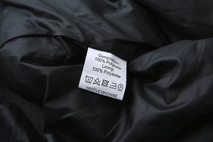 Détail de l'étiquette d'entretien montrant la composition 100% polyester sur veste noire