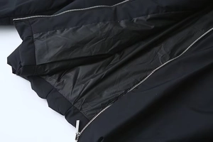 Détail de la fermeture éclair argentée et de la doublure sur une veste noire femme