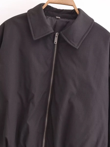 Détail d'une veste noire à revers montrant la texture lisse et la fermeture éclair en argent