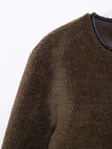 Detailed macro view of dark brown faux fur jacket with black leather trim craftsmanship