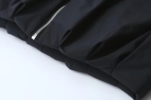 Détail de la fermeture éclair en métal argenté sur une veste matelassée noire mate