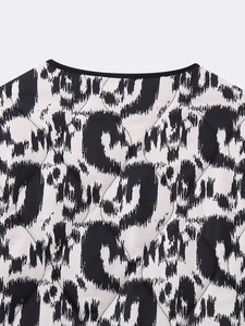 Detail of quilted leopard print jacket featuring a round neckline and black edge piping