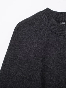 Detailed close-up of dark grey round neck knit coat with ribbed collar and brand label