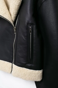 Détail d'une veste en simili cuir avec doublure polaire crème et fermeture éclair en métal