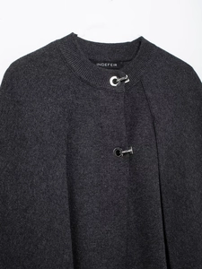 Close-up of charcoal grey knit poncho coat featuring unique silver G-shaped buckles