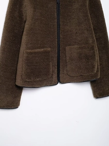 Detail of fleece jacket featuring textured plush fabric and black leather piping trim