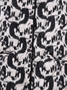 Detail shot of black and white leopard print quilted jacket with snap buttons and pockets