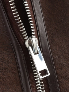 Detailed close-up of premium metal zipper and brown suede texture on a fashion jacket