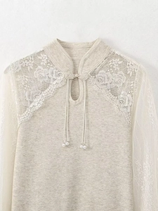 Detail of beige knit top with delicate lace rose patterns and pearl bead accents