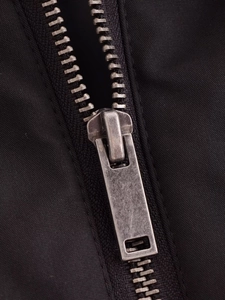 Détail d'une fermeture éclair en métal argenté sur un tissu en sergé noir de veste