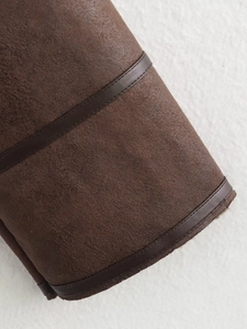 Detailed close-up of dark brown suede jacket cuff with premium leather piping trim