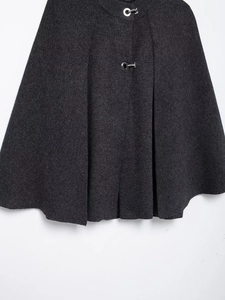 Close-up of dark grey knit poncho featuring stylish silver horseshoe metal buckles